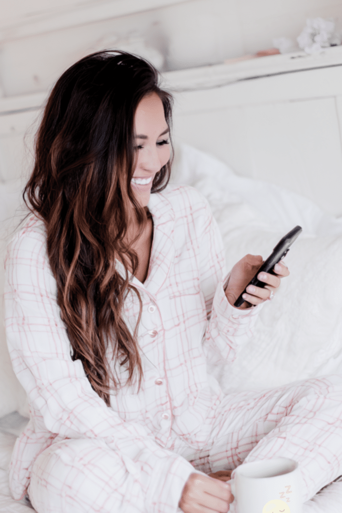woman sitting in bed looking at her phone