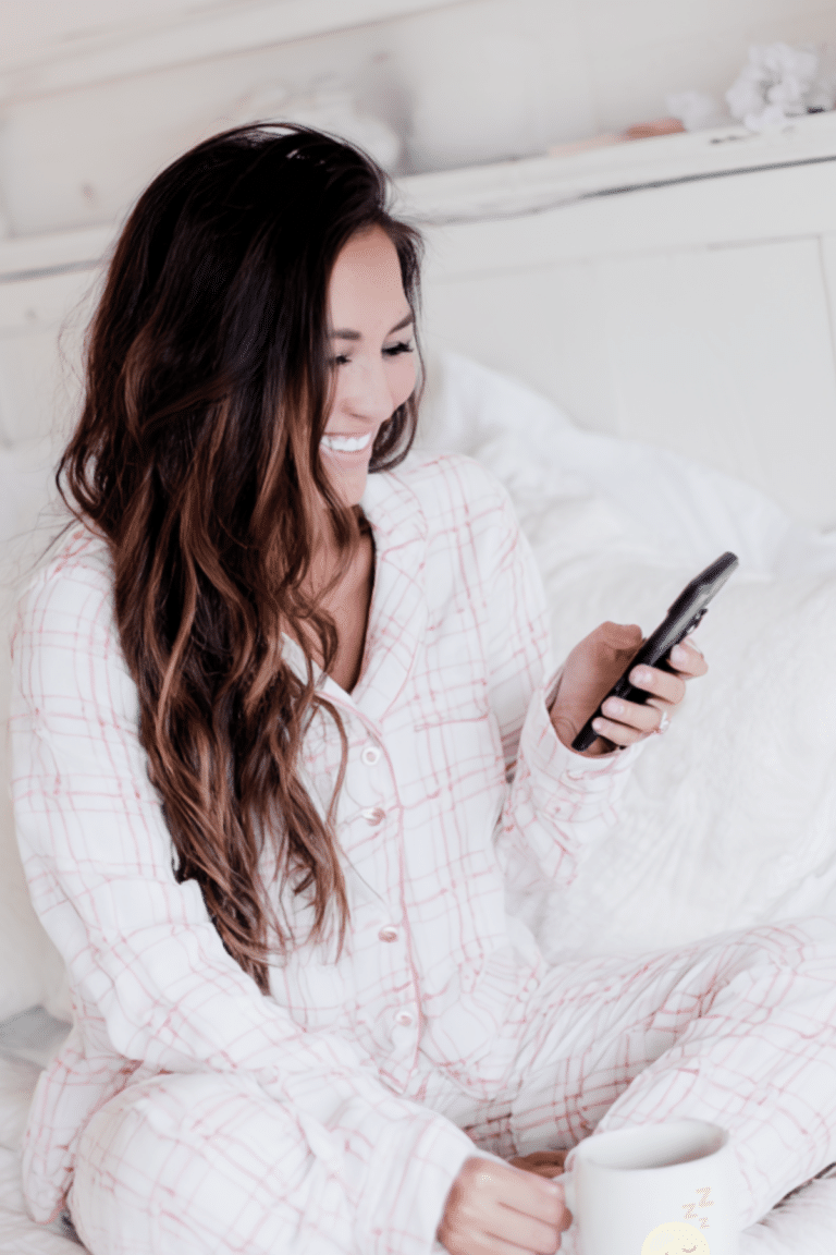 woman sitting in bed looking at her phone